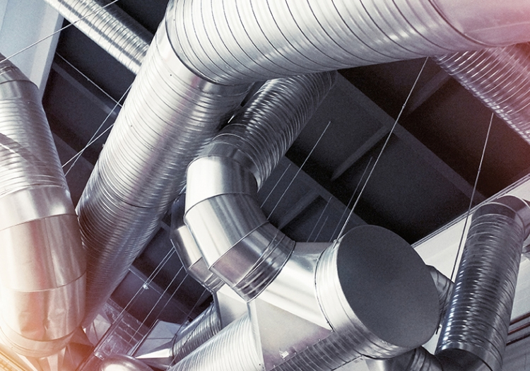 Intricate network of metallic ducts and pipes, part of an industrial HVAC system, showing complex interconnections for climate control