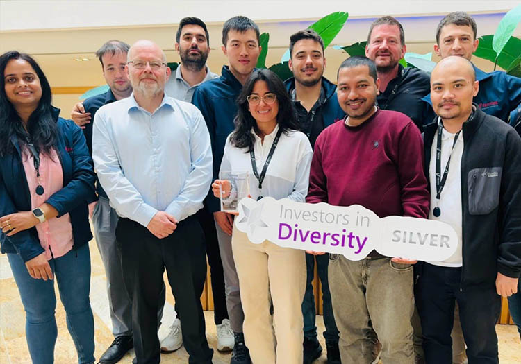 Group of team members standing indoors holding an ‘Investors in Diversity Silver’ award plaque