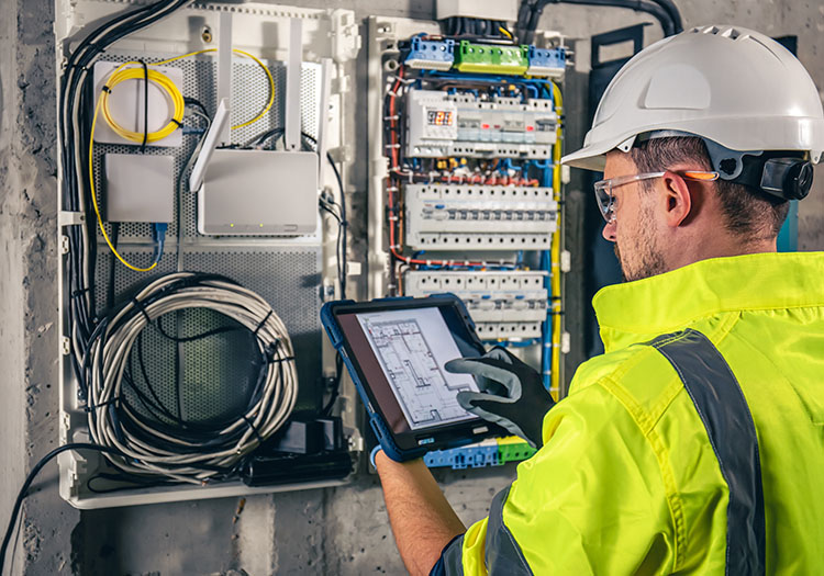 Electrical engineer inspecting switchboard using tablet in modern building design Ireland
